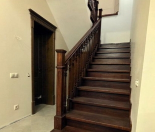 Фото лестницы с отделкой дубом тёмного ореха и дизайнерскими деревянными столбами