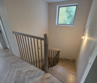 Фото лестницы из бетона с облицовкой канадским дубом и гнутым дубовым поручнем