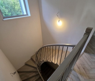 Фото лестницы с дубовыми ступенями и поручнем из гнутого дуба на металлических стойках