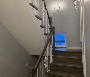 Фото лестницы в Плещеницах — дуб на бетонных ступенях, ажурные балясины, тёмный оттенок дерева.